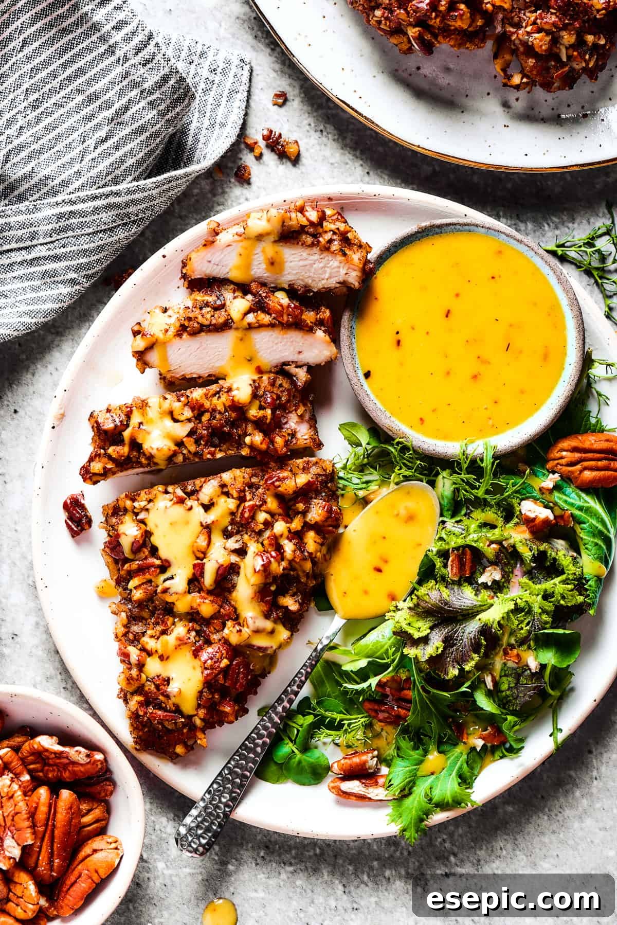 A breast of chicken cooked in pecan breading, sliced and served on a dinner plate.