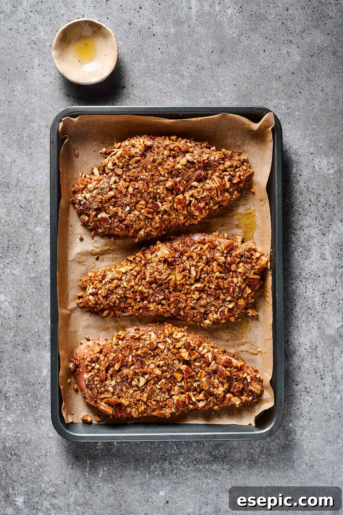 Pecan-coated chicken on a baking sheet.