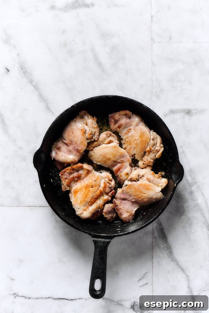 Velvety Chicken Gnocchi Delight 2 Chicken thighs browning in a skillet, developing a golden crust.