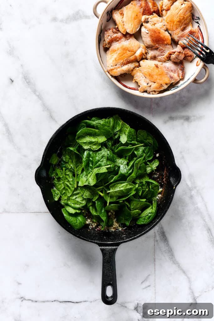 Velvety Chicken Gnocchi Delight 3 Baby spinach wilting in a skillet with garlic, releasing its moisture.