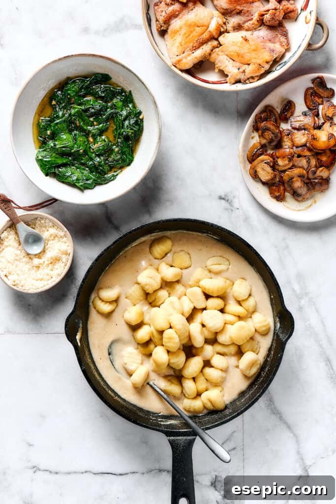 Velvety Chicken Gnocchi Delight 6 Cooked gnocchi added to the cream sauce in a skillet, next to dishes of spinach, mushrooms, and chicken.