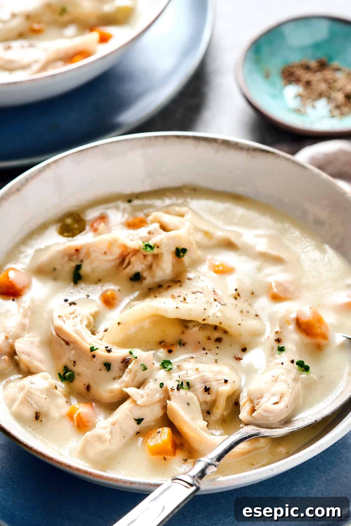 Southern-style Chicken and Dumplings are made with soft rolled dumplings, a rich, creamy broth, with tender pieces of white meat chicken. Creamy chicken and dumplings served into bowls.