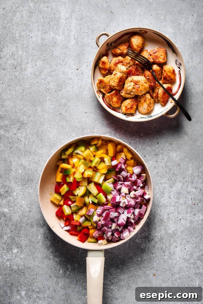 Chopped vegetables in a skillet next to a bowl of cooked chicken.