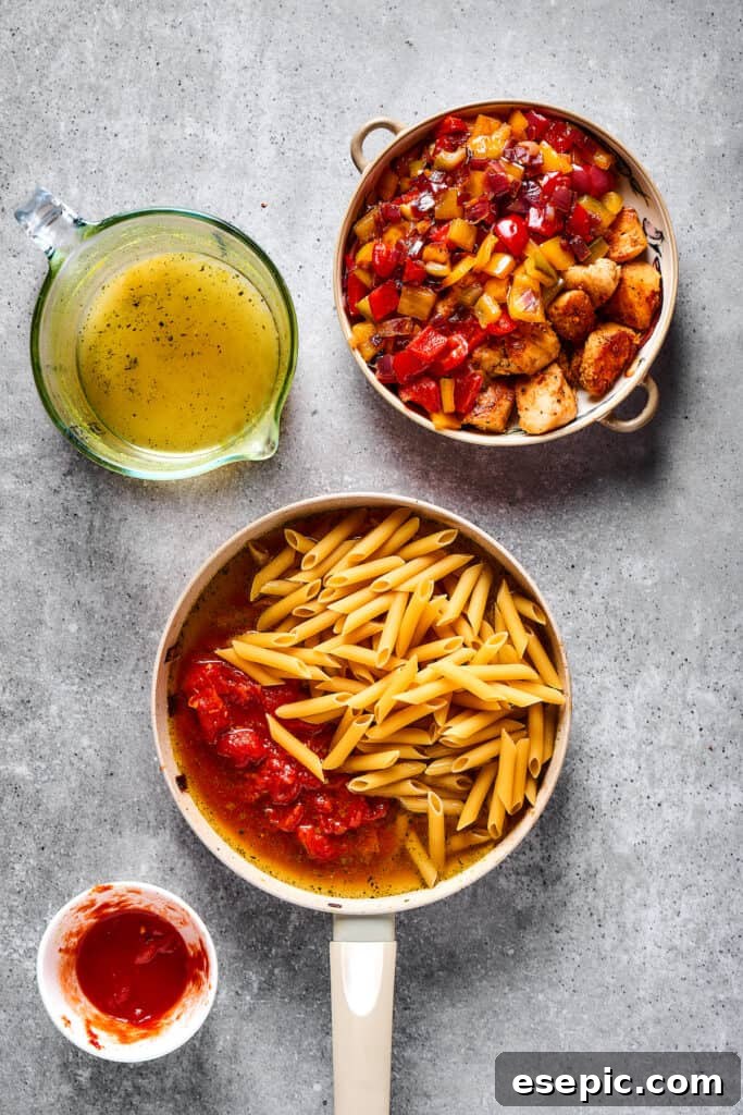 Pasta, tomatoes, and broth combined in a skillet next to a dish of cooked chicken and vegetables.