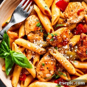 overhead close up of chicken and penne with tomatoes, peppers, and onions.
