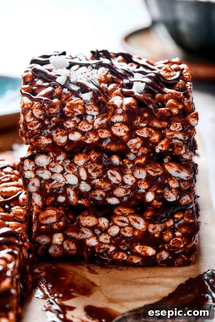 Irresistible Chocolate Crispy Bars 9 A stack of delicious chocolate rice krispie treats, generously drizzled with chocolate topping and sprinkled with sea salt.