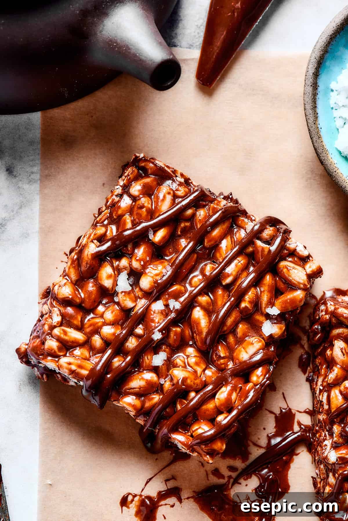 Close-up of a perfectly crafted chocolate rice krispie square. A single square of chocolate rice and marshmallow treat, drizzled with chocolate, on a textured background.