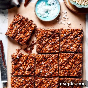 Squares of chocolate rice krispie treats next to a bowl of flaky sea salt.