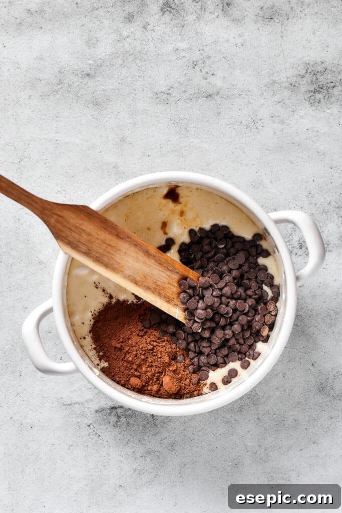 Irresistible Chocolate Crispy Bars 4 Chocolate chips and cocoa powder being stirred into the melted butter and marshmallow mixture, creating a rich brown color.