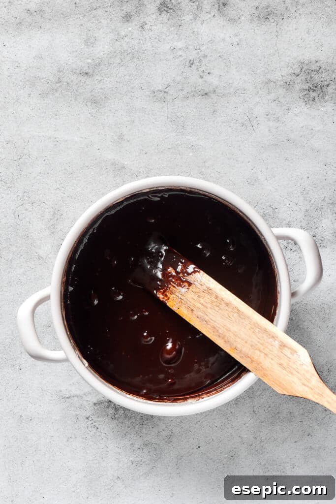 Irresistible Chocolate Crispy Bars 5 A pot filled with a glossy, dark chocolate marshmallow mixture, perfectly combined and ready for cereal.