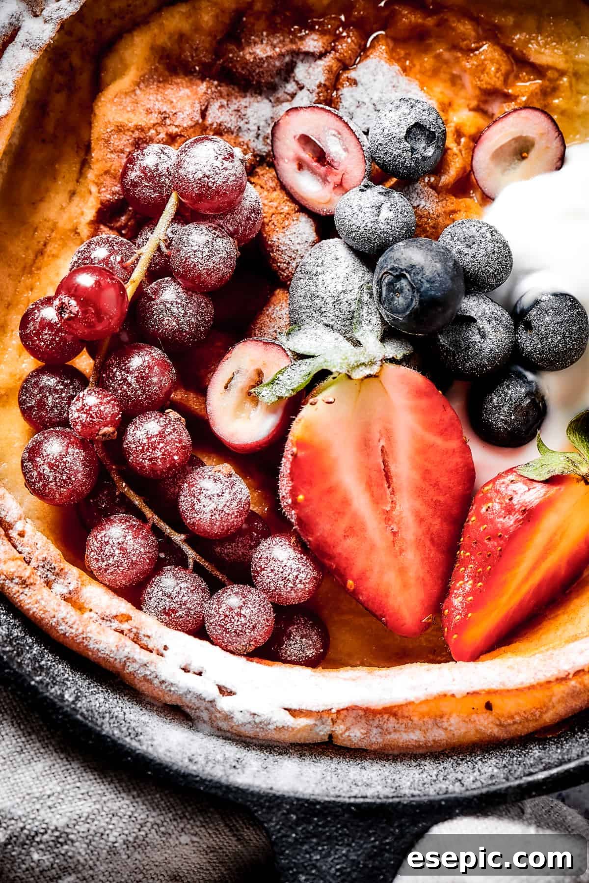 A German pancake topped with powdered sugar and fresh fruit.