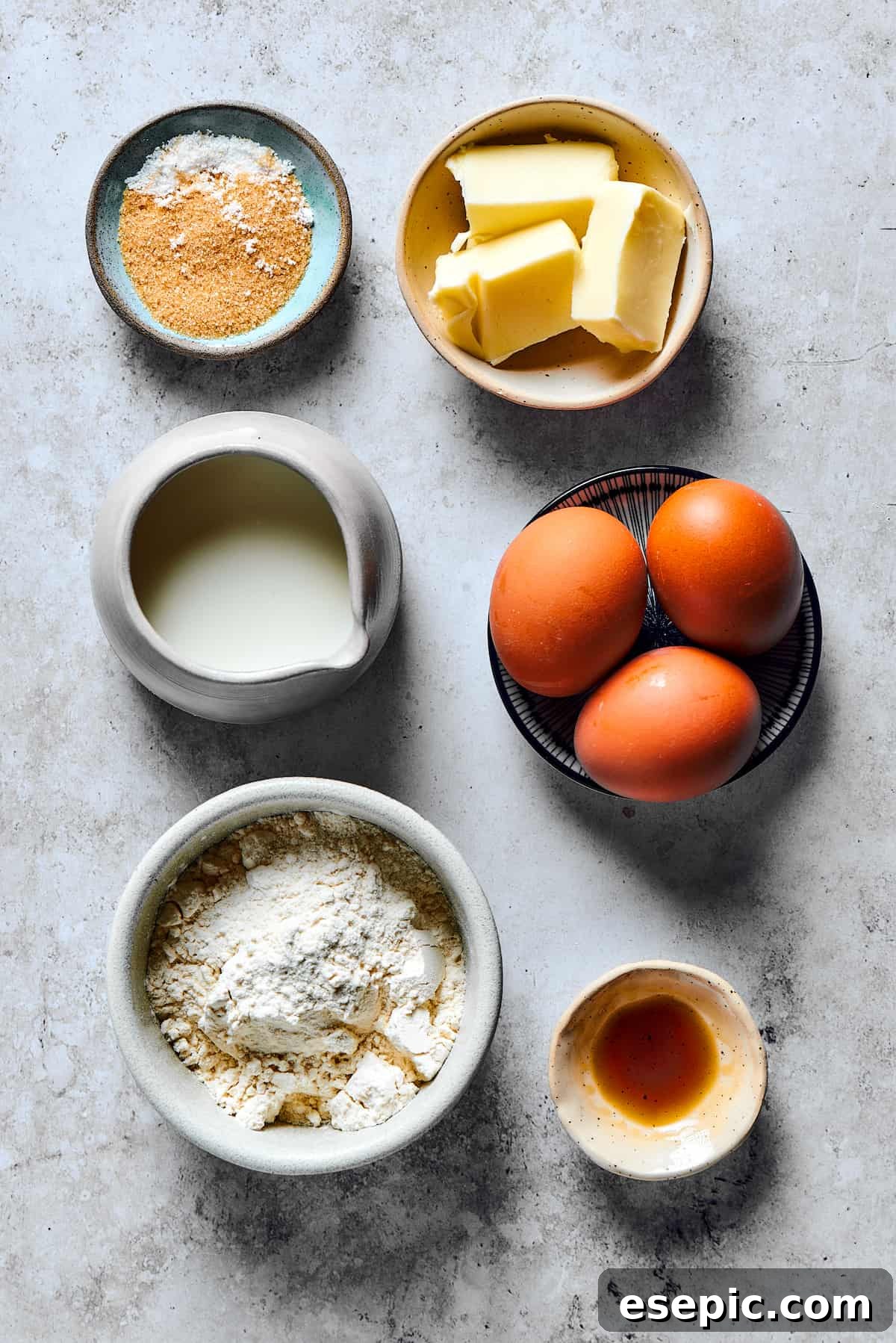 Ingredients for a Dutch baby pancake measured into small dishes and arranged on a work surface.