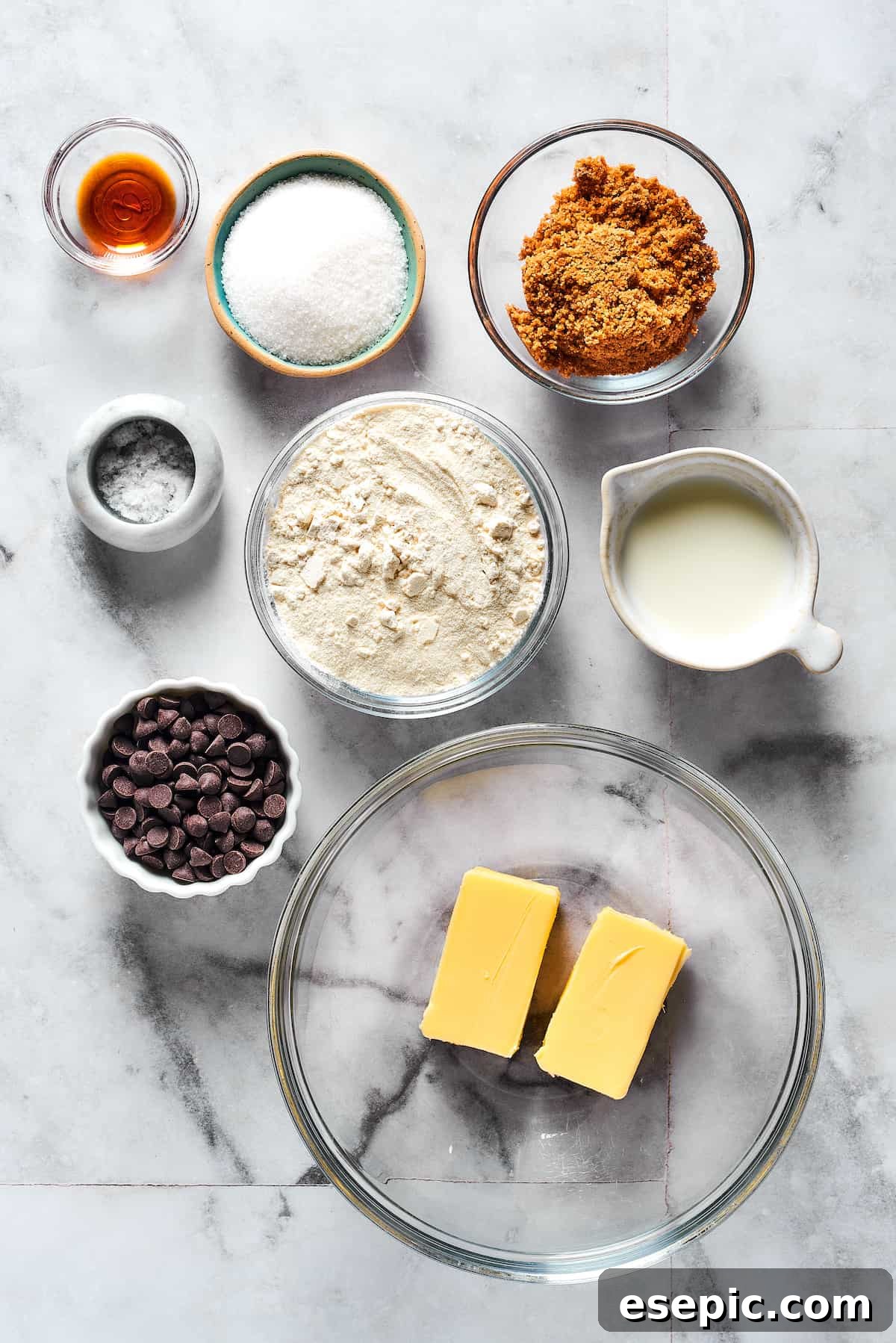 From top: Vanilla, granulated sugar, brown sugar, salt, flour, milk, chocolate chips, butter, neatly laid out as ingredients for edible cookie dough.
