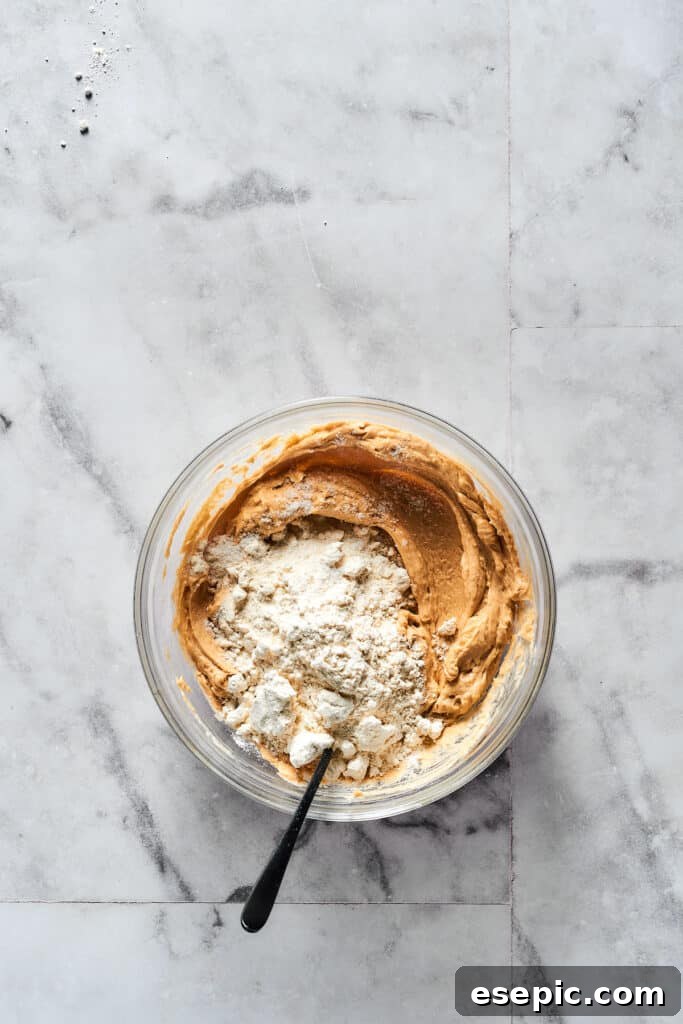 Mixing dry and wet ingredients for edible cookie dough, demonstrating the combining process.