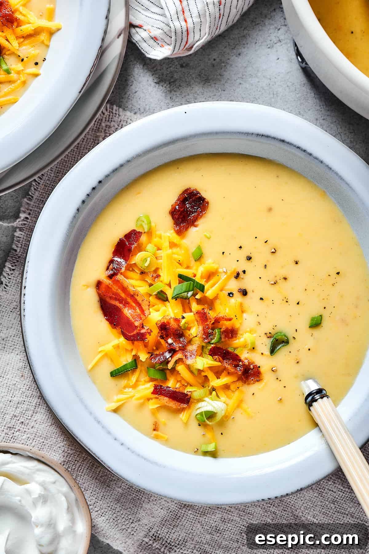 A steaming bowl of Loaded Baked Potato Soup, generously topped with crispy bacon, shredded cheddar cheese, and freshly chopped green onions, ready to be enjoyed.