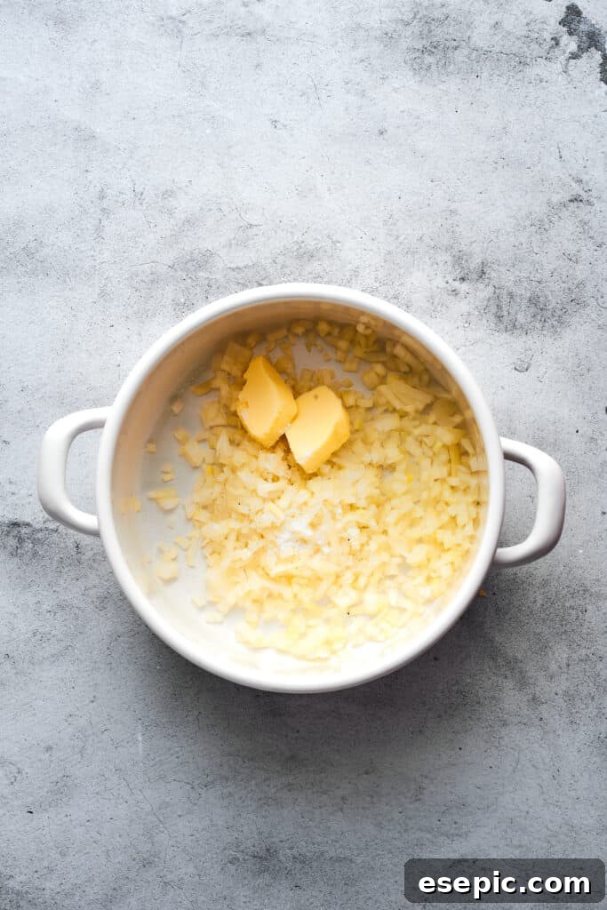 Chopped onions and melting butter gently cooking in a large soup pot over medium heat, releasing their sweet aroma and softening.