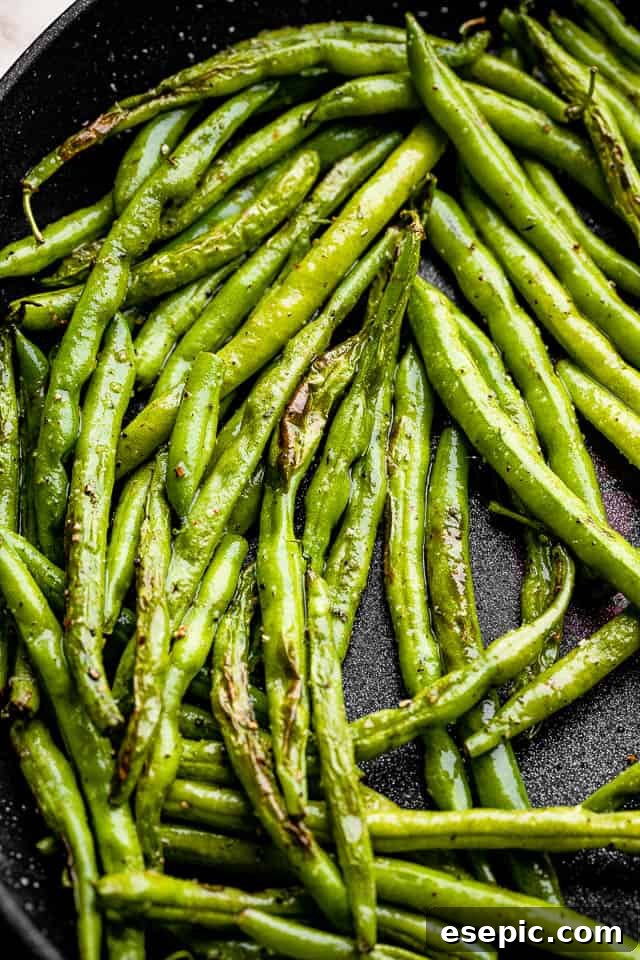 Bright green beans sizzling in a sleek black skillet, ready to be seasoned and cooked to tender-crisp perfection.