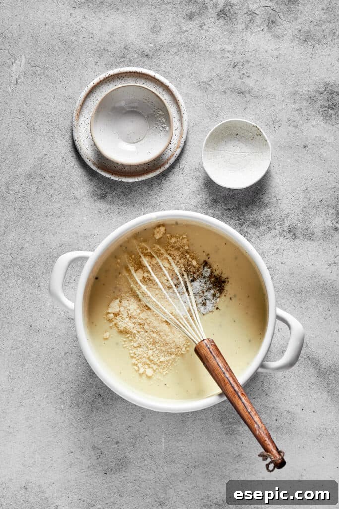 A creamy sauce being whisked in a pot, ensuring a smooth consistency for the chicken tetrazzini.
