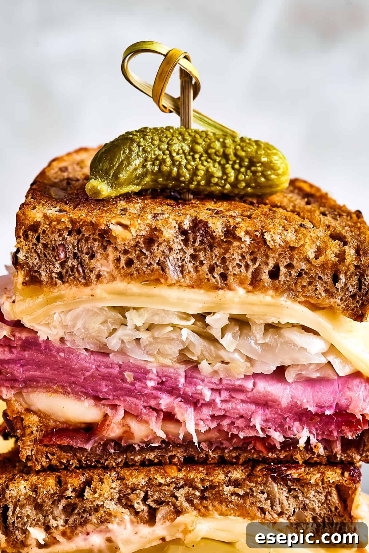 A pair of stacked sandwich halves held together with a decorative skewer.