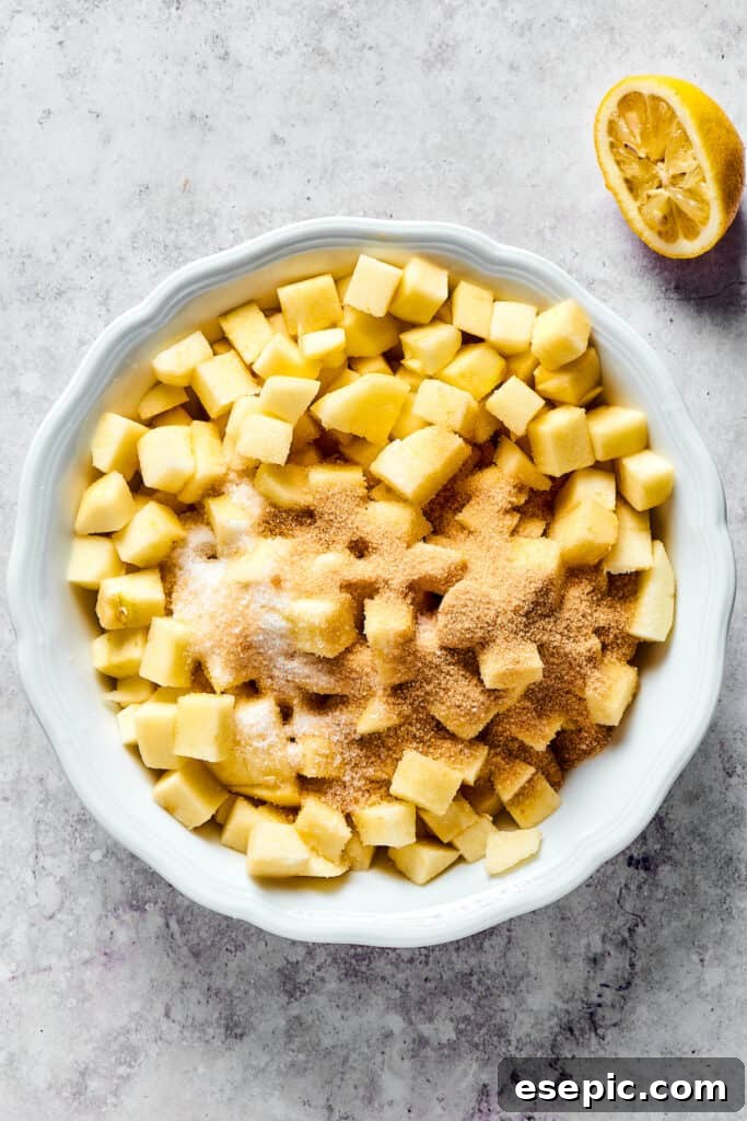 Diced apples drizzled with lemon juice and sprinkled with sugar and spices, ready for cooking.
