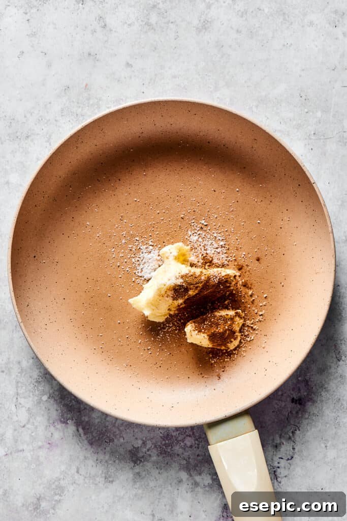 Melted butter infused with cinnamon and nutmeg in a hot skillet, creating an aromatic base for the apple pie filling.