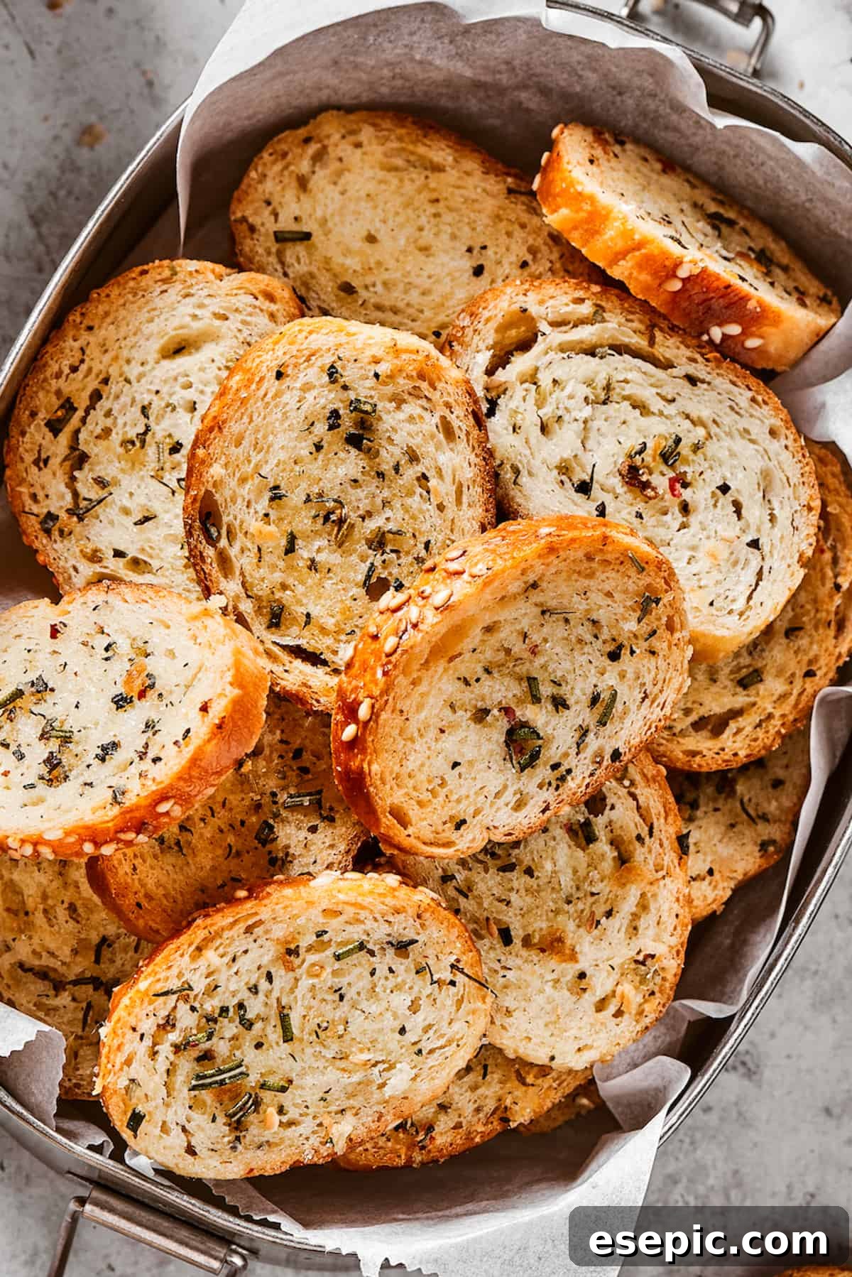 Seasoned and baked bagel chips in a metal tin, perfectly golden and crispy.
