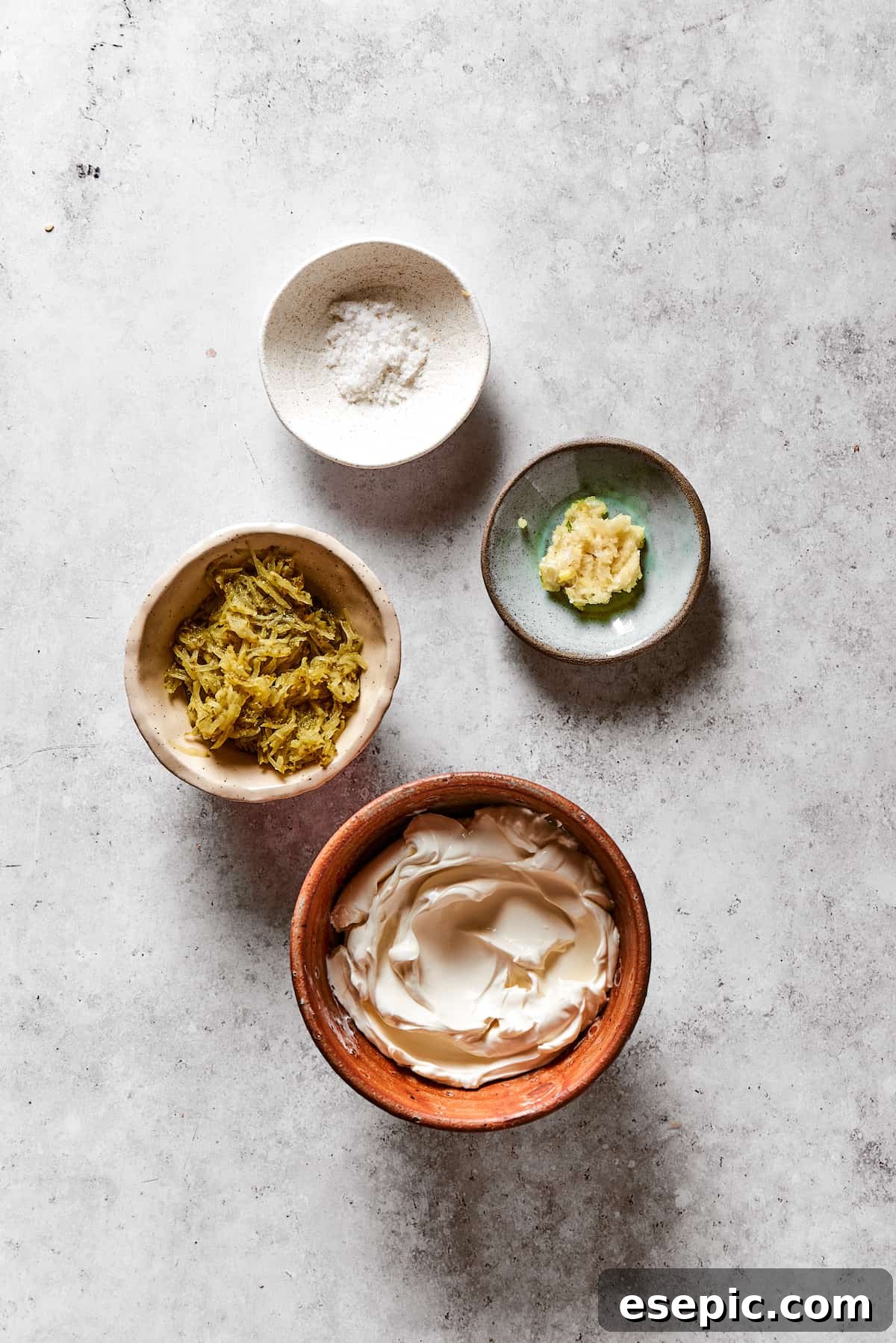 Various dip ingredients laid out: cream cheese, chopped pickles, salt, and garlic.