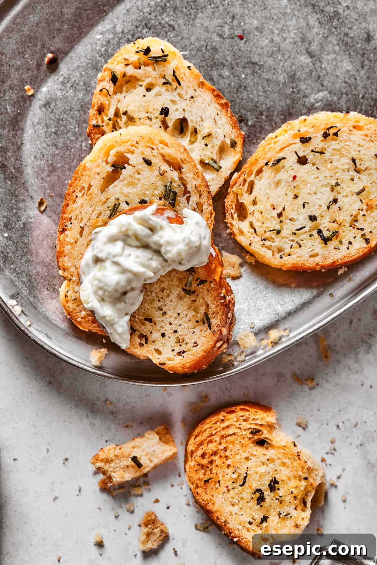 A few baked bagel chips, one perfectly dipped in creamy dip, showcasing its delicious appeal.