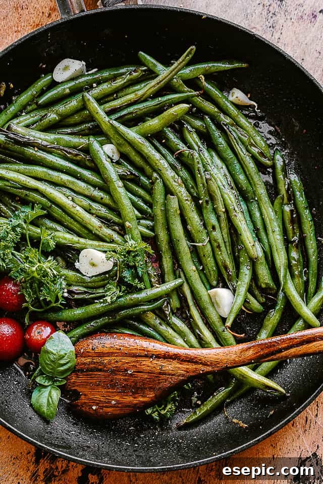 green beans cooking in a black skillet, perfectly charred and glistening with butter