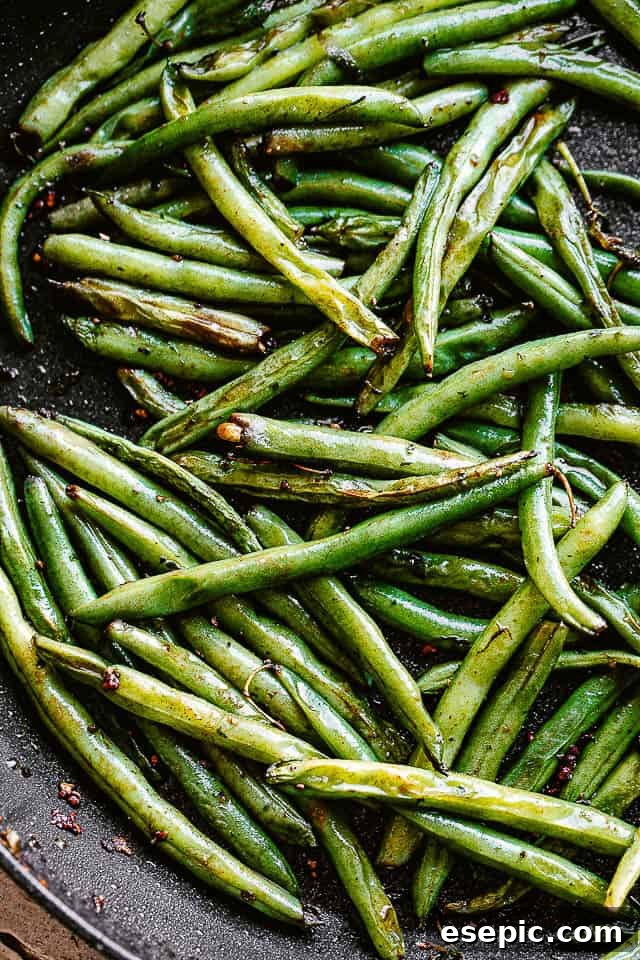Fresh green beans getting pan-fried in a skillet with butter and olive oil.