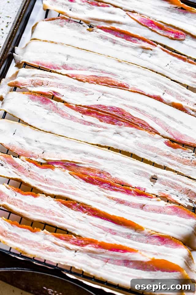 Raw bacon slices arranged on an oven-safe wire rack, ready for baking.