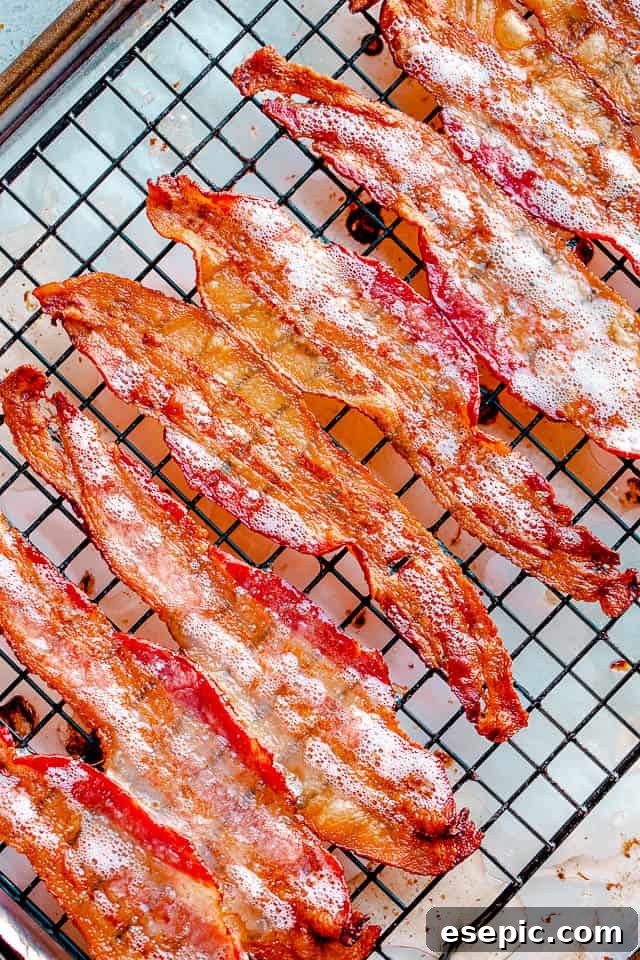 Oven-baked bacon cooking on a wire rack inside the oven, showing early stages of crisping.