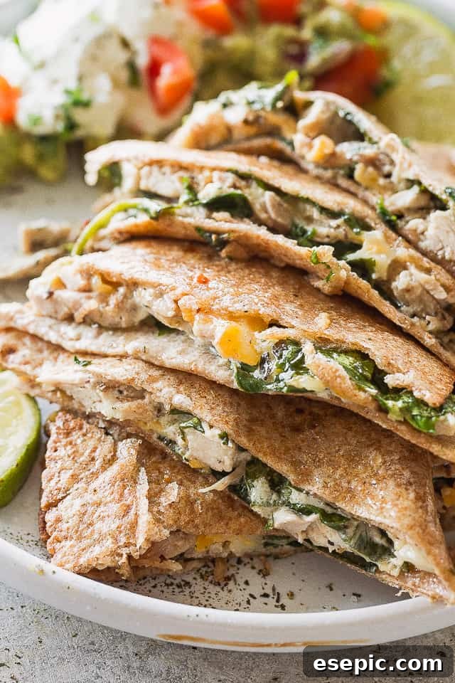 These baked chicken quesadillas are stuffed with fresh spinach, melted cheese and shredded chicken. It's 100% kid approved and oh so good! A plate of chicken quesadillas cut in half, showcasing the crispy tortillas and melted filling.