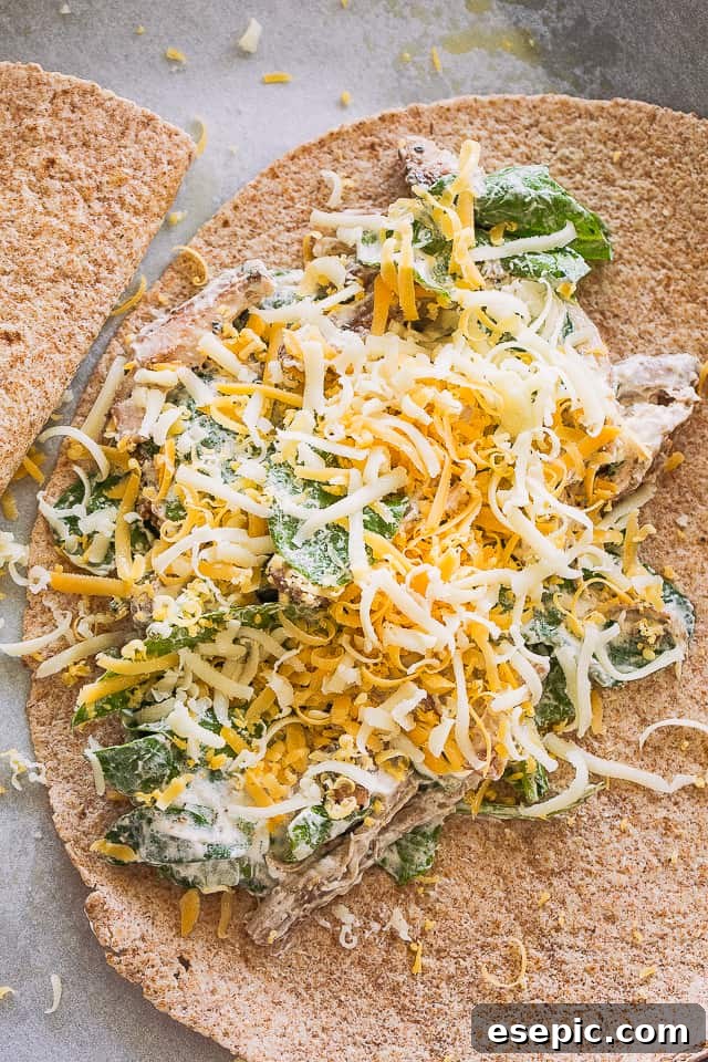 These baked chicken quesadillas are stuffed with fresh spinach, melted cheese and shredded chicken. It's 100% kid approved and oh so good! Adding the chicken and cheese mixture to one half of a flour tortilla.