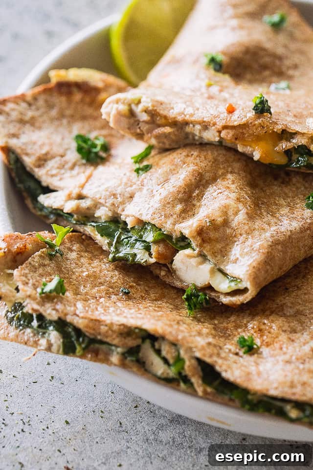 These baked chicken quesadillas are stuffed with fresh spinach, melted cheese and shredded chicken. It's 100% kid approved and oh so good! Close-up shot of crispy baked chicken and cheese quesadillas, showcasing the golden-brown tortilla.