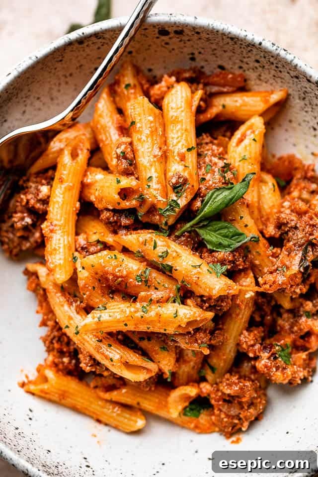 The Ultimate Cheesy Baked Ziti 5 A deep serving bowl filled with a generous portion of freshly baked ziti, featuring melted cheese and a hearty ground beef sauce, ready to be enjoyed.