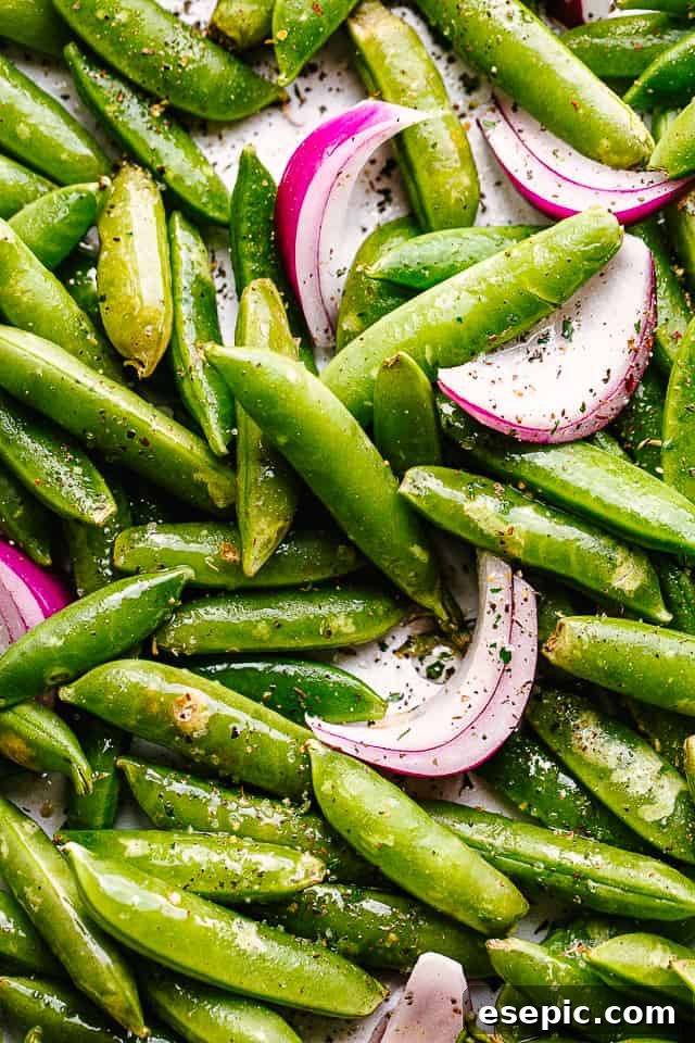 close up of raw snap peas and onions tossed with seasonings