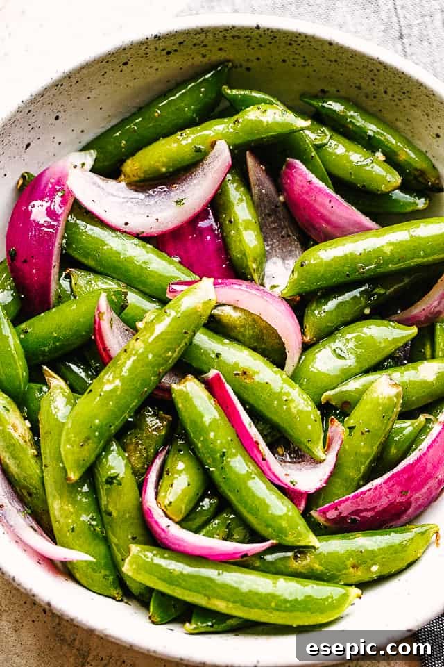 roasted sugar snap peas with red onions served in a cream bowl