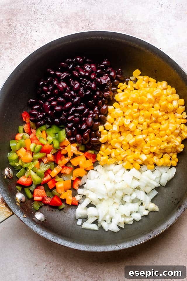 frying peppers, beans, corn, and onions in a frying pan