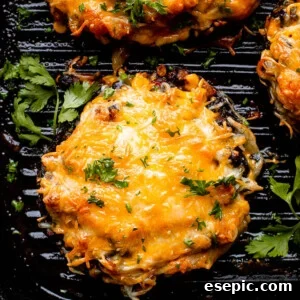 A close-up shot of two grilled portobello mushrooms, richly stuffed with black beans and corn, topped with beautifully melted, bubbly cheese.
