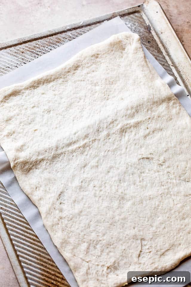 Raw pizza dough, perfectly shaped and ready on a baking sheet, awaiting its delicious transformation on the grill.