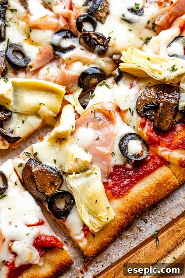 A delicious square slice of grilled Capricciosa pizza, showcasing its tempting layers of ham, olive slices, and artichoke hearts, ready to be picked up.