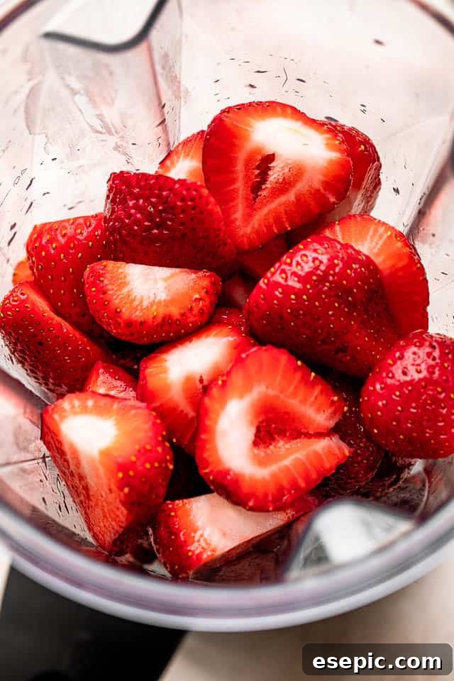 Freshly washed strawberries in a high-powered blender, ready for blending.
