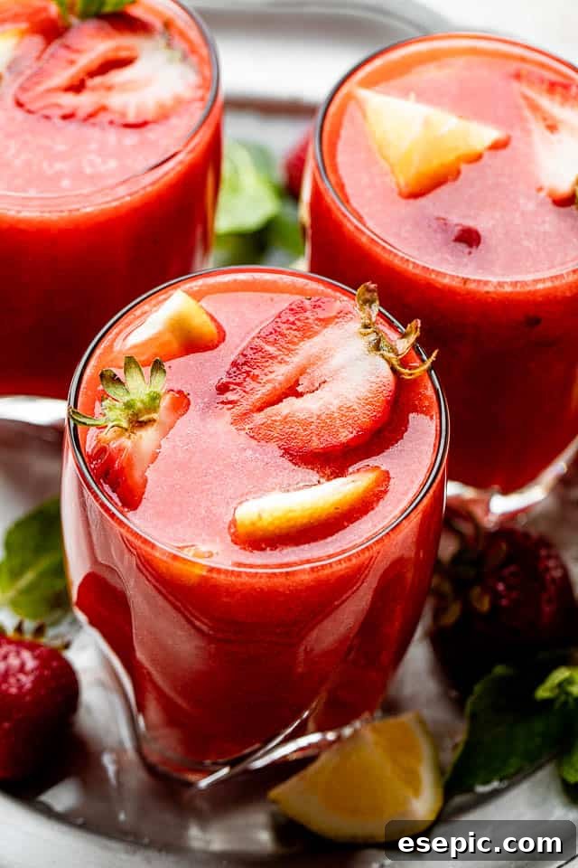 Two short glasses filled with Strawberry Lemonade Sangria, garnished with strawberry slices and lemon wedges.