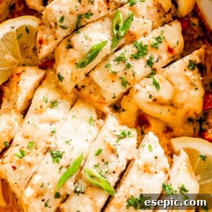 Close-up shot of sliced baked chicken breasts topped with Caesar dressing and parsley