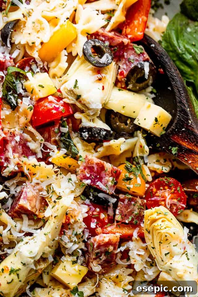 Italian Deli Pasta Salad 4 close up shot of a salad bowl filled with pasta, cheese cubes, salami cubes, tomatoes, and olives