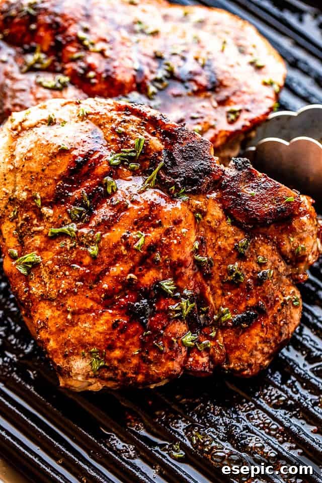 Tongs turning over perfectly charred and juicy grilled pork chops on the grill