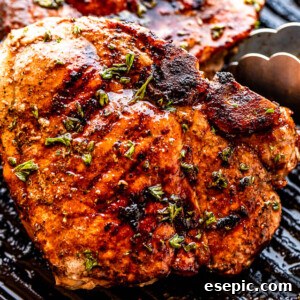 Grilled pork chops being turned on the grill with tongs