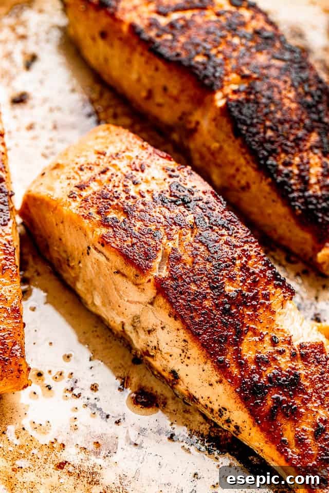 Close-up overhead view of four pan-seared salmon fillets, showing their perfectly crispy skin and tender, pink flesh, ready for the creamy dill sauce.
