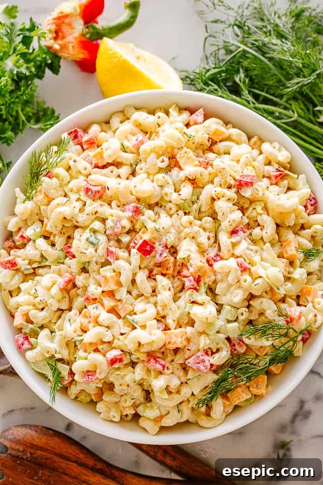 A beautifully presented bowl of creamy macaroni salad, garnished with fresh herbs, ready to be served at a family gathering or a summer barbecue.